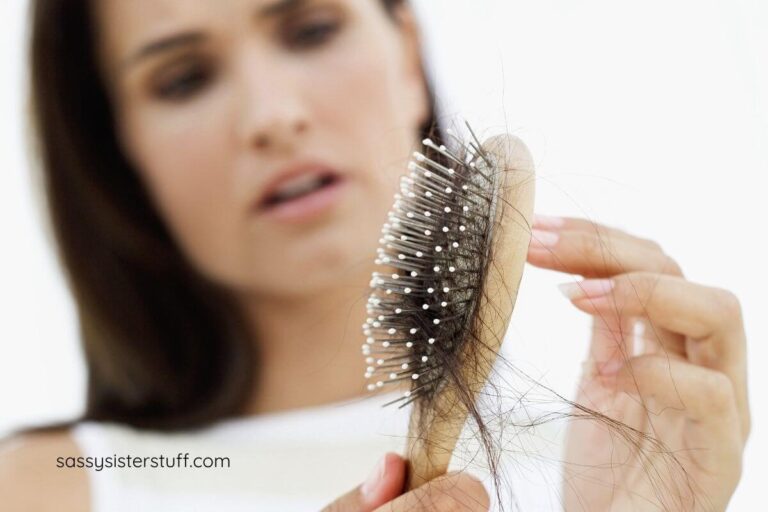 beautiful woman looking upset at her brush full of broken hair.