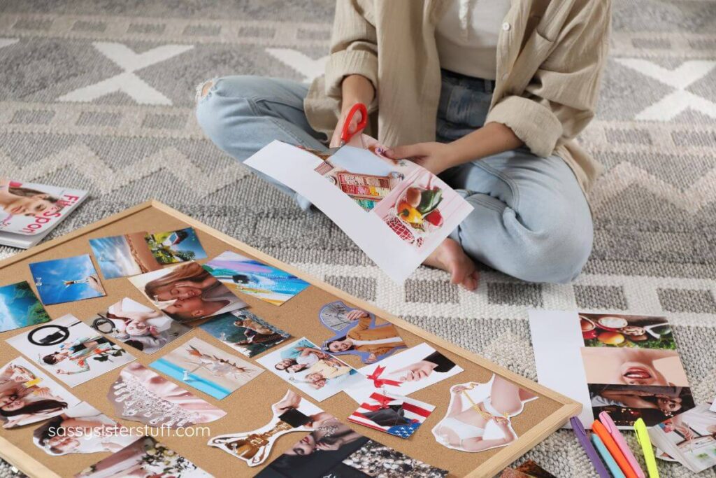 a woman sits on the floor with her craft supplies and works on her vision board.