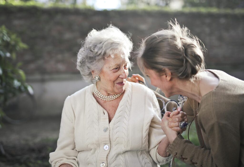 Joyful interaction between an elderly woman and her granddaughter in a sunny outdoor setting.Andrea Piacquadio