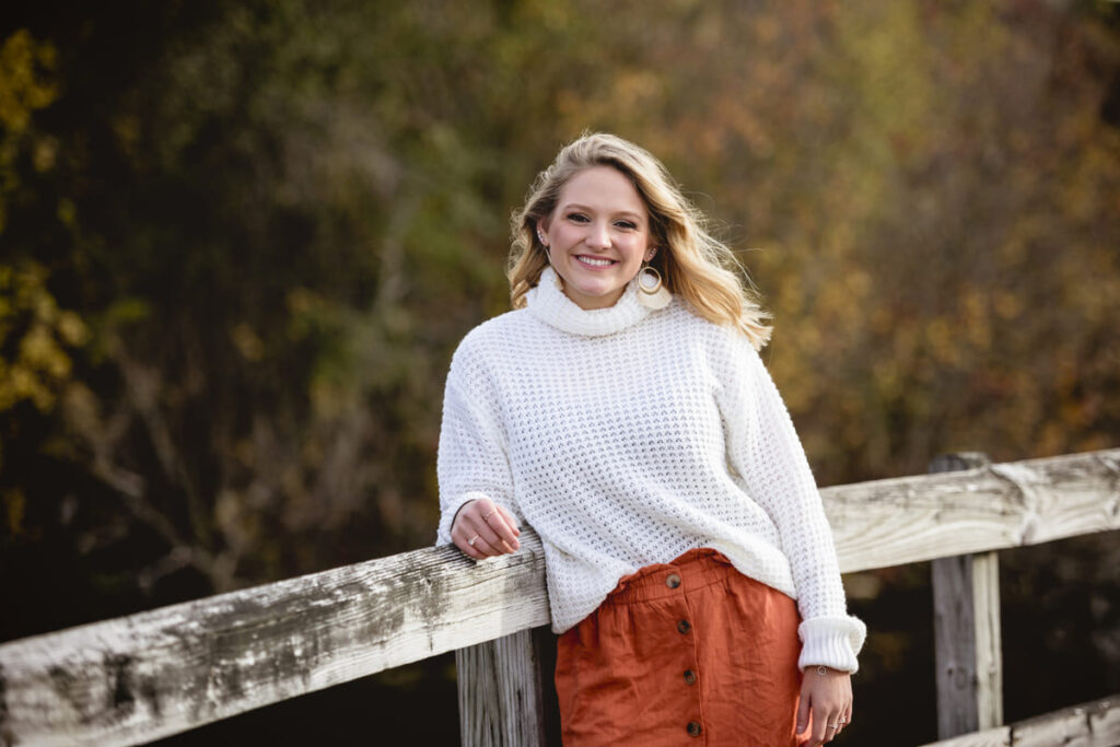 Woman leaning against a wooden fence and smiling