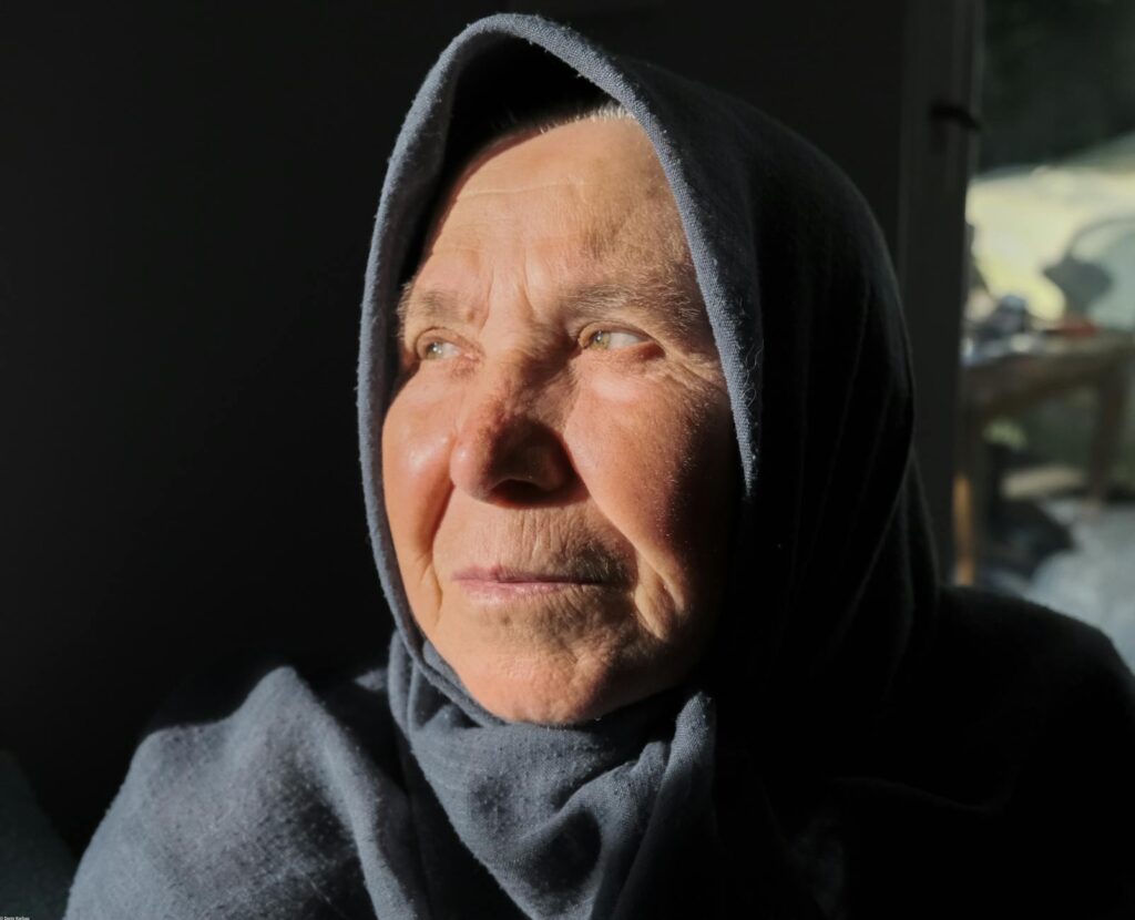 Portrait of a senior woman wearing a headscarf bathed in warm sunlight looking pensive.Deniz Karbas