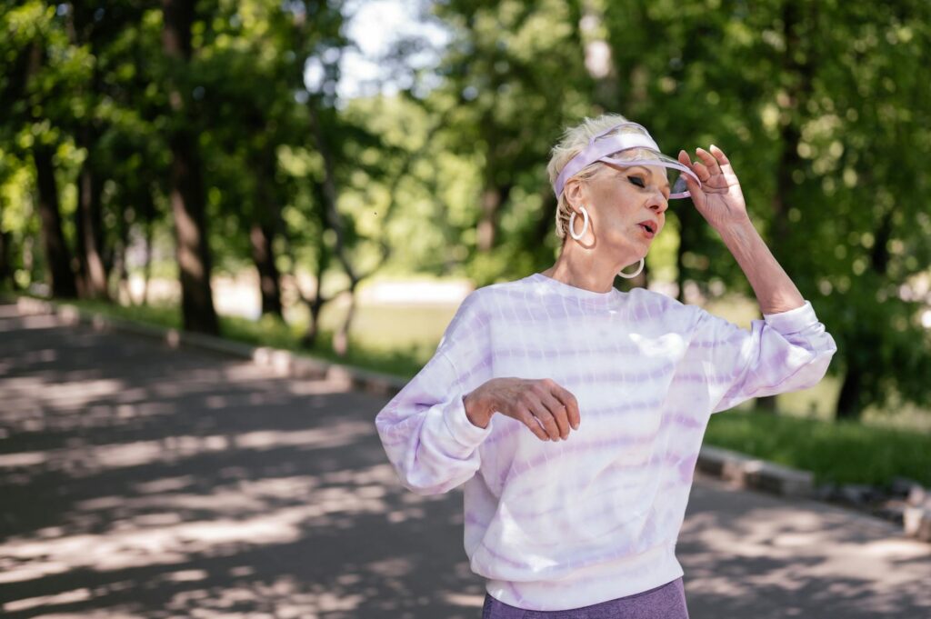 Senior adult woman outdoors in a park taking a break during a workout wearing casual sportswear.SHVETS production