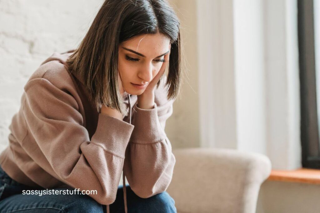 young woman holds her hands up to the sides of her head in deep thought as she decides how to respond when someone says you're too sensitive.