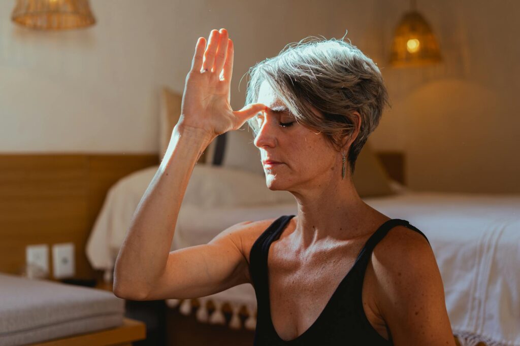 Serene elderly woman practicing yoga meditation indoors symbolizing wellness and positive aging.Los Muertos Crew