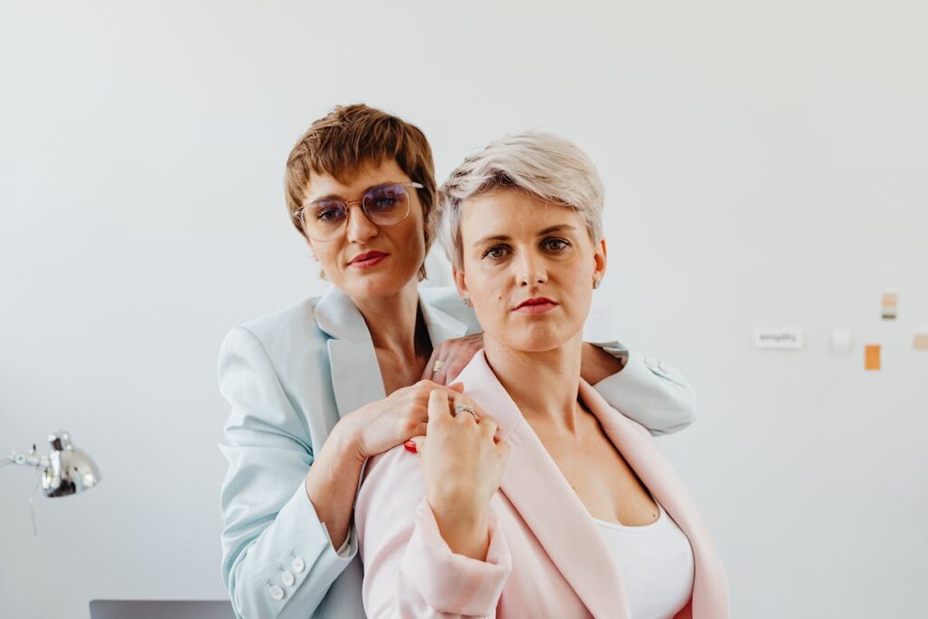 Woman in White Blazer Standing Behind a Woman in Pink Blazer