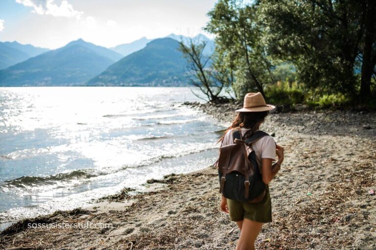 solo woman traveler walking along a beach with mountains in the background.