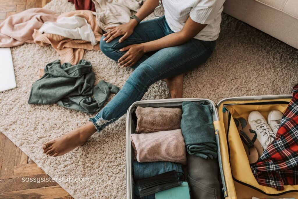 woman sitting on the floor using travel tips for women over 50 to organize her suitcase in preparation for solo travel.