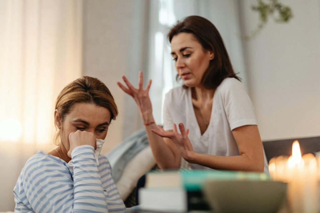 Two women engage in an emotional conversation indoors addressing issues and stress.Photo By Kaboompics.com