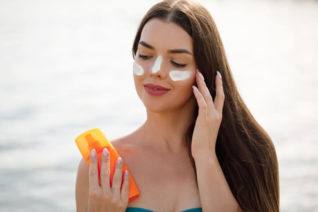 Woman smile applying sun cream on face Skincare Body Sun protection