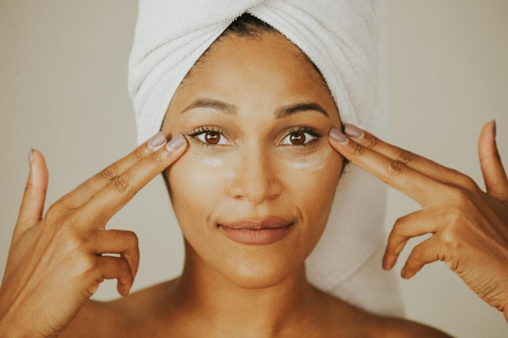 Woman applying facial cream with a towel wrapped on her head highlighting skincare routine.Misolo Cosmetic