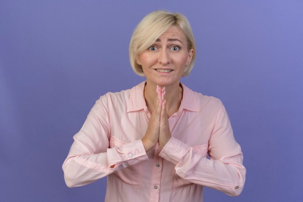 Begging young blonde slavic woman keeping hands together isolated on purple background
stockking
