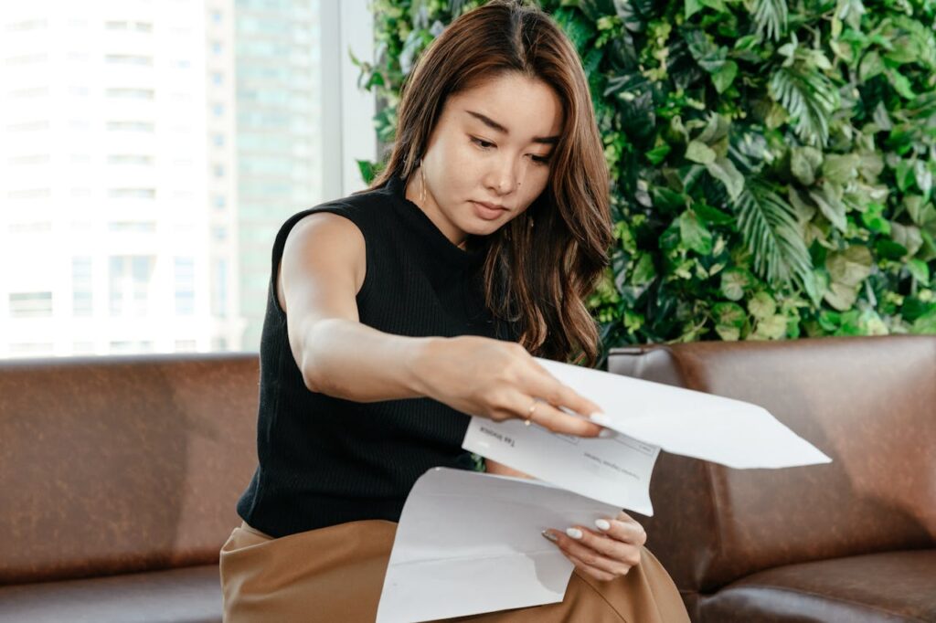 Serious Asian woman reading documents on couch