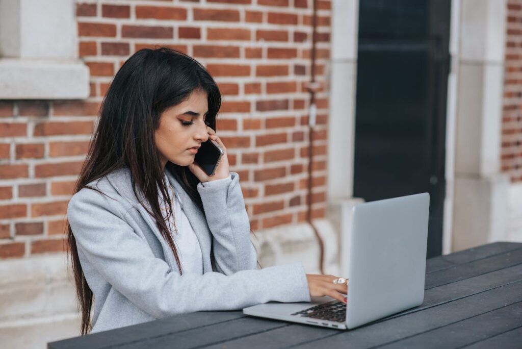 Serious ethnic entrepreneur talking on smartphone while working on laptop