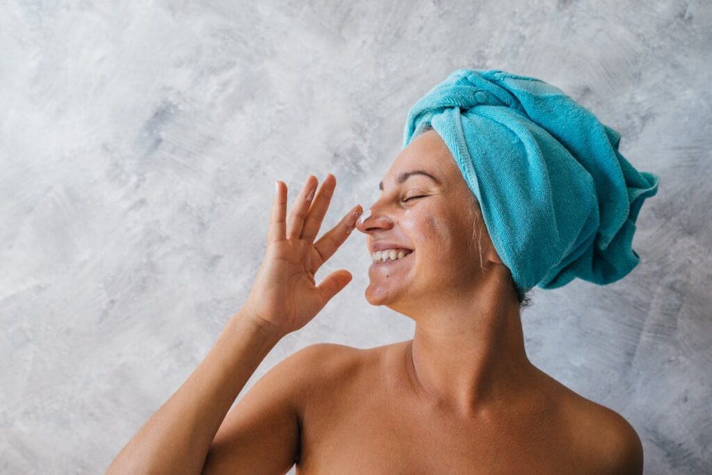 A Smiling Woman Putting Facial Cream on Nose