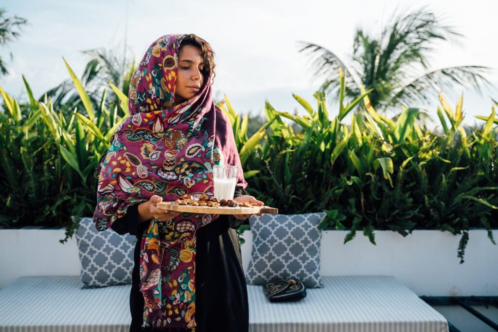 A Woman Carrying a Wooden Tray with Dates and a Glass of Milk