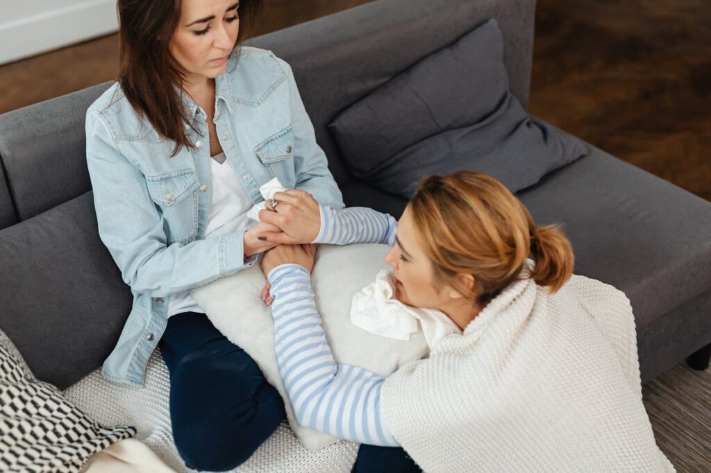 Woman in a Denim Jacket Holding Hands with a Crying Woman