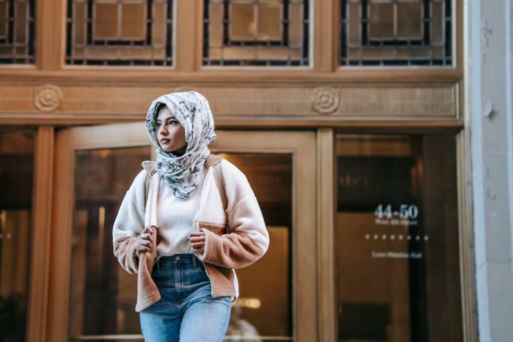 Pensive young Arab female millennial standing near entrance of aged building
