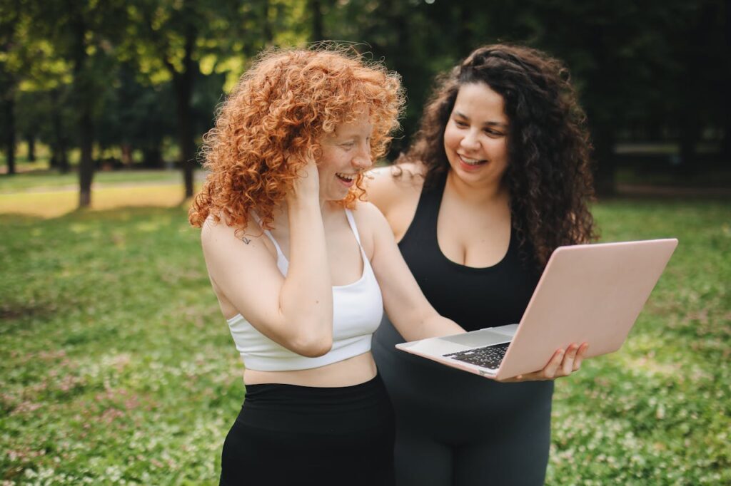 Woman in White Brassier and Black Leggings Holding Pink Laptop