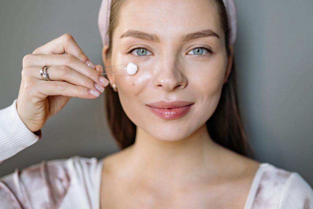 Woman applying beauty product on her face
