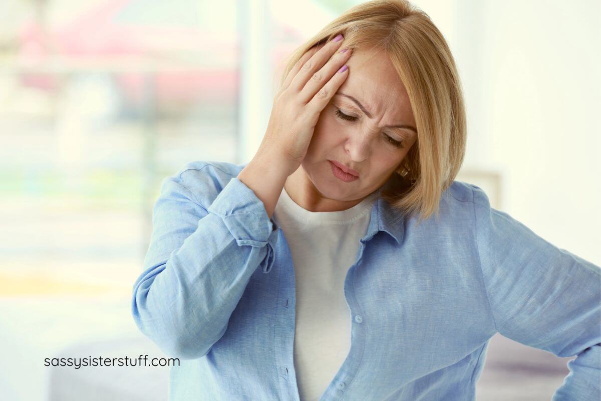 middled aged woman holds her head and appears to be in upset.