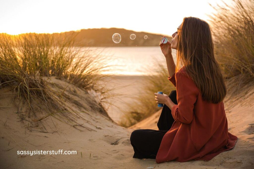 woman sitting on the beach blowing bubbles to relax.