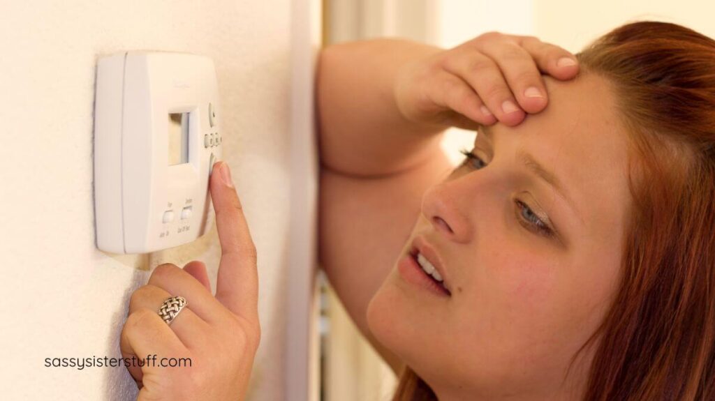 middle aged woman changing the thermostat because of her hot flashes.