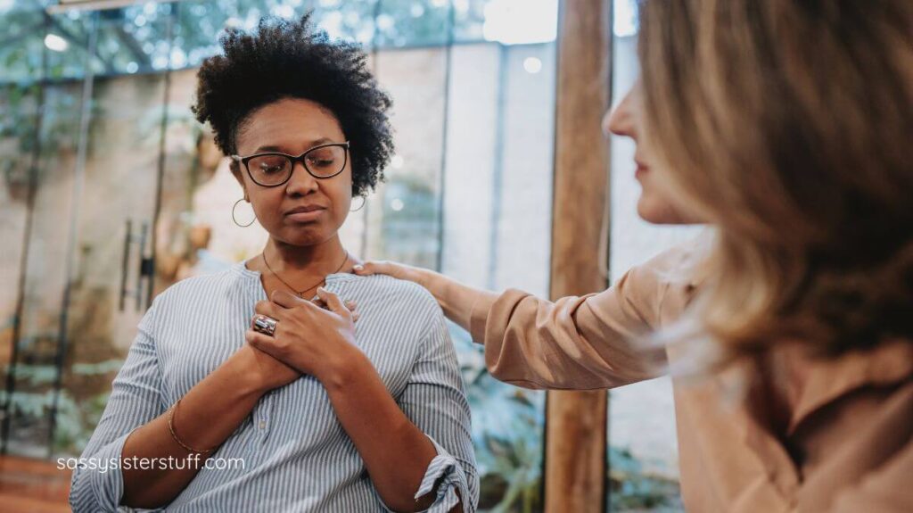 a friend with her hand on her friend's shoulder as a sign of support.