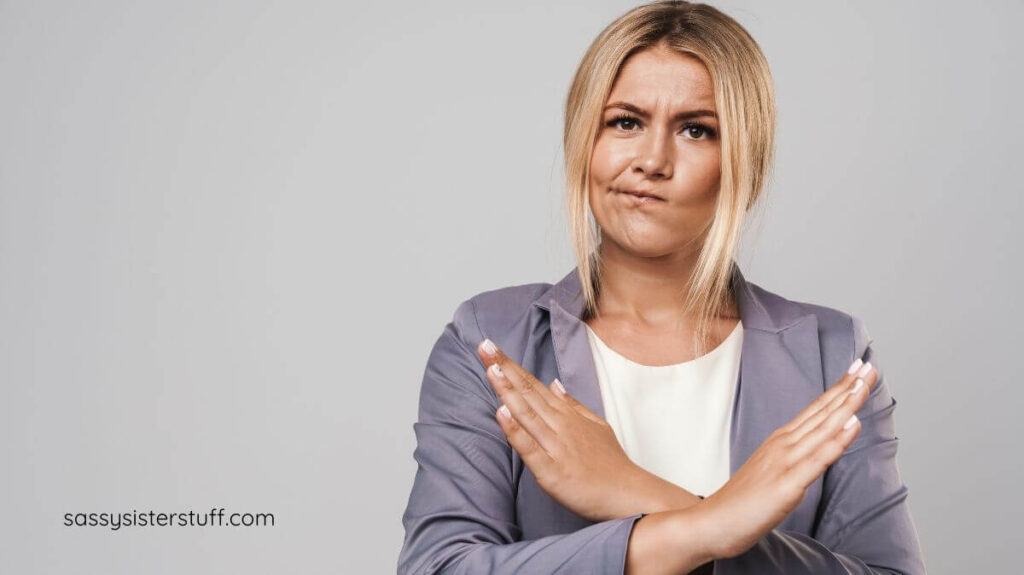 a woman with her hands crossed over her chest to indicate NO.
