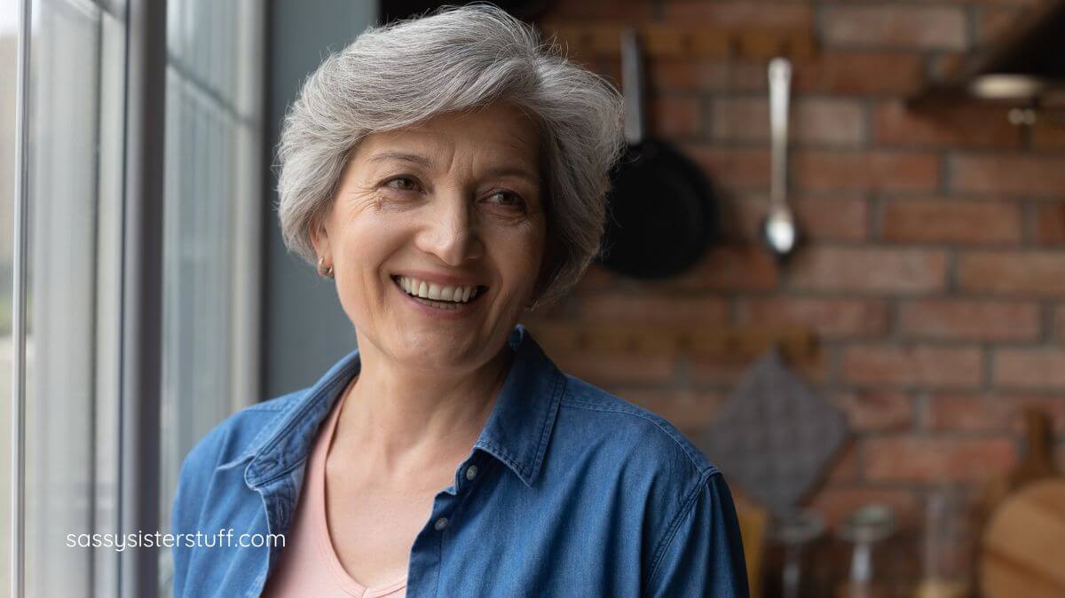 middle aged woman with beautiful silver hair smiling confidently over her shoulder.