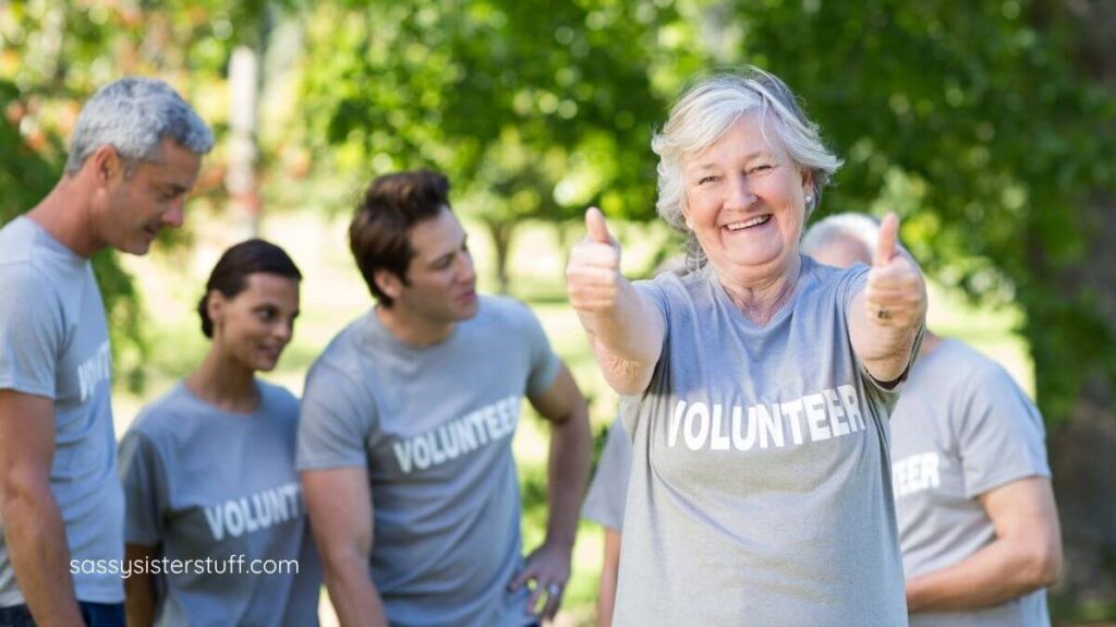 older woman giving a thumbs up while working with a group of volunteers.