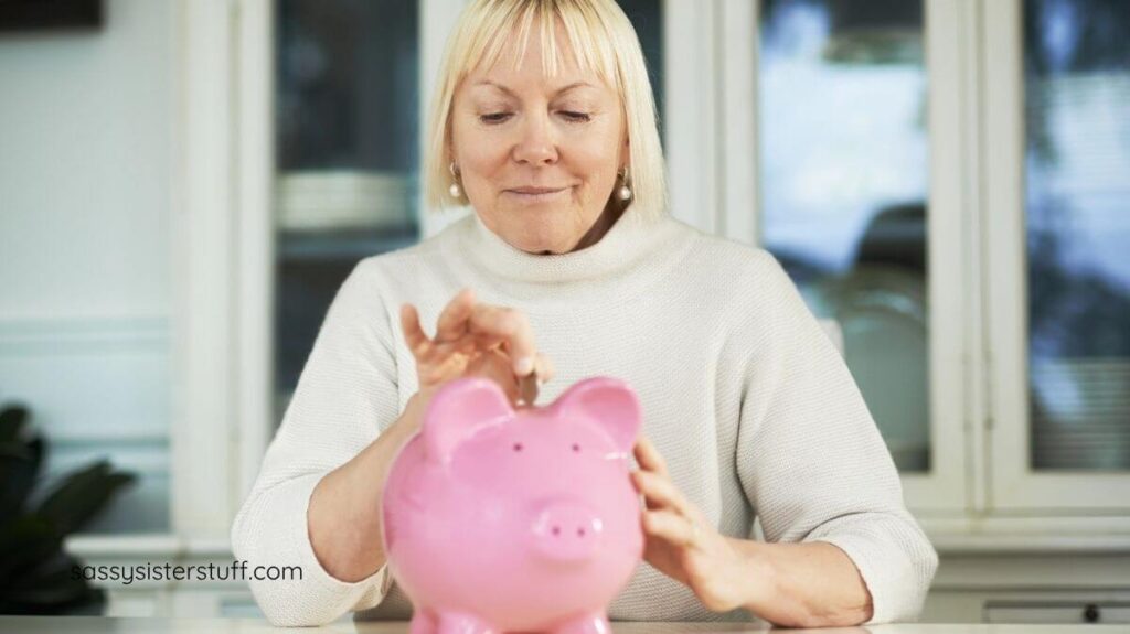 middle aged woman putting money in a pink piggy bank.