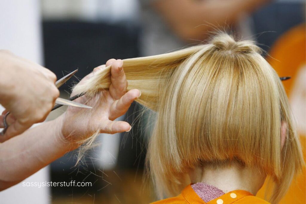woman getting her hair professionally trimmed in a salon.