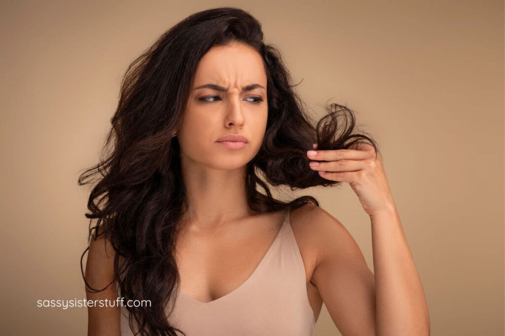 frustrated woman looking at the ends of her dry hair.