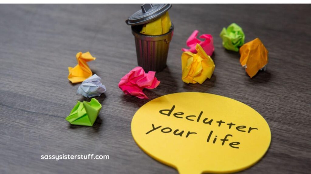 top view of a sticky note that says declutter your life and crumpled up sticky notes laying around it.