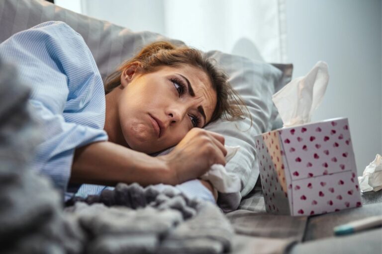 woman laying on the couch sad with a box of kleenex