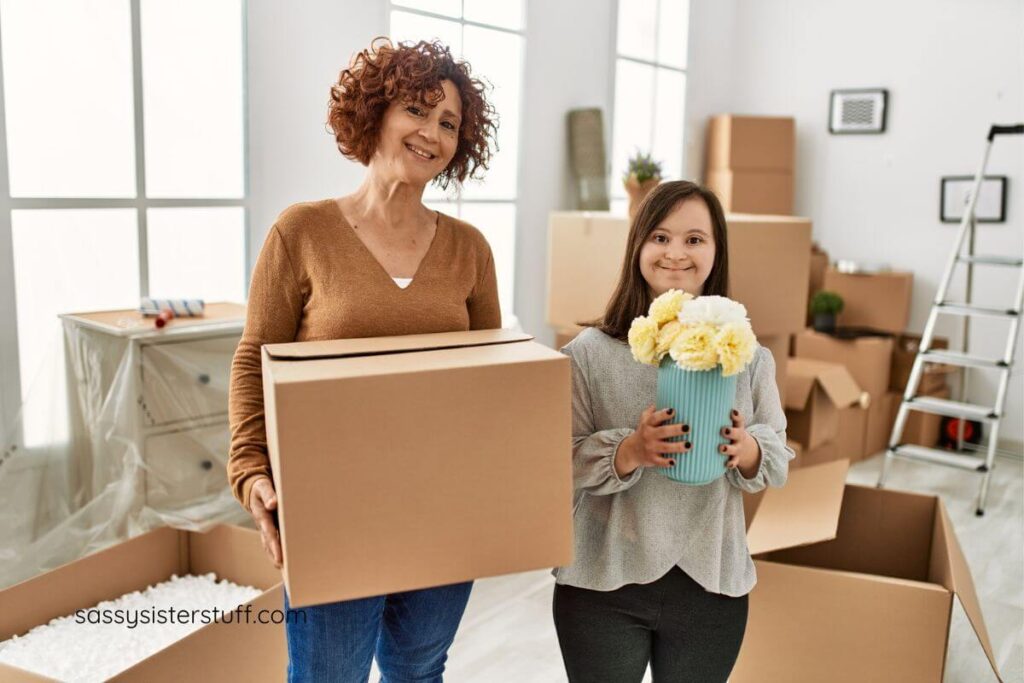 middle aged mom and her adult child with down syndrome pack boxes to move to a new home.