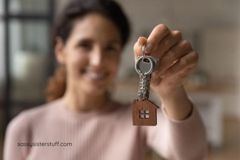 a woman holds her new house key up for a photo.