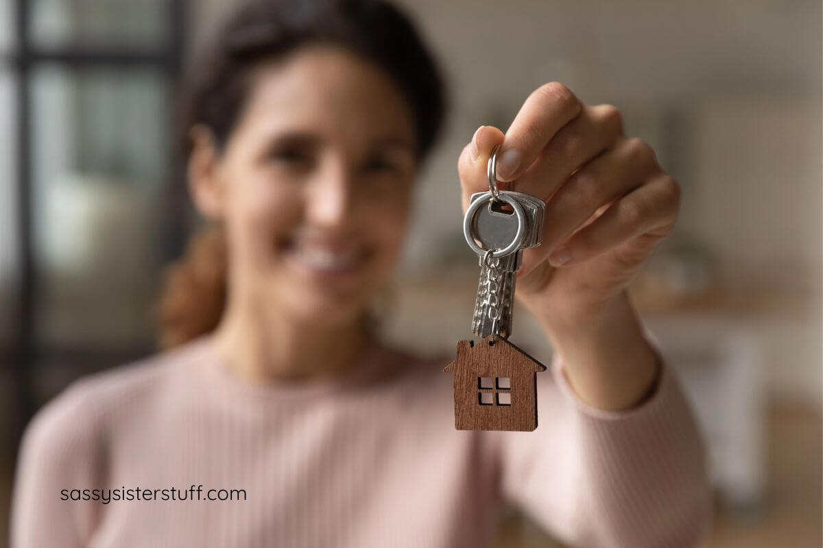 a woman holds her new house key up for a photo.
