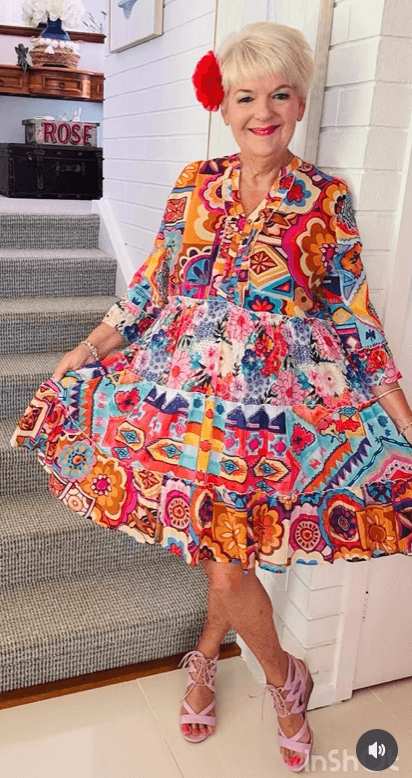 beautiful older woman dressed in bright, bold colored dress with a flower in her hair.