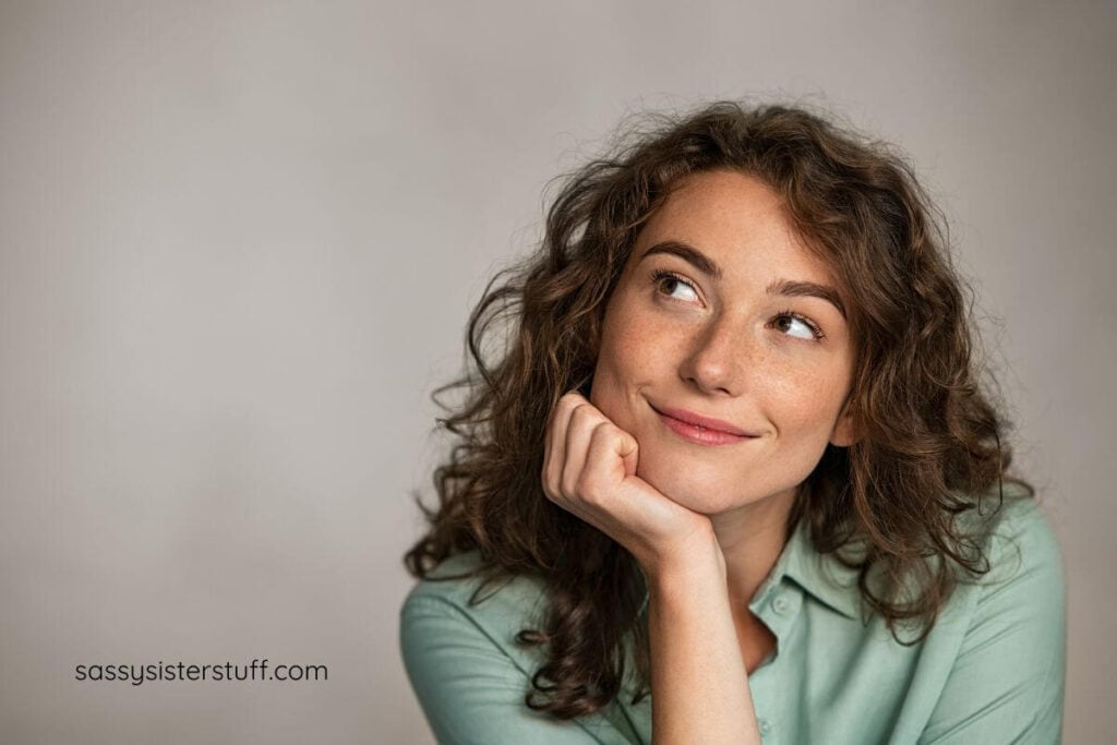 cute young woman with freckles smiling up at the ceiling thinking of affirmations for overthinking.