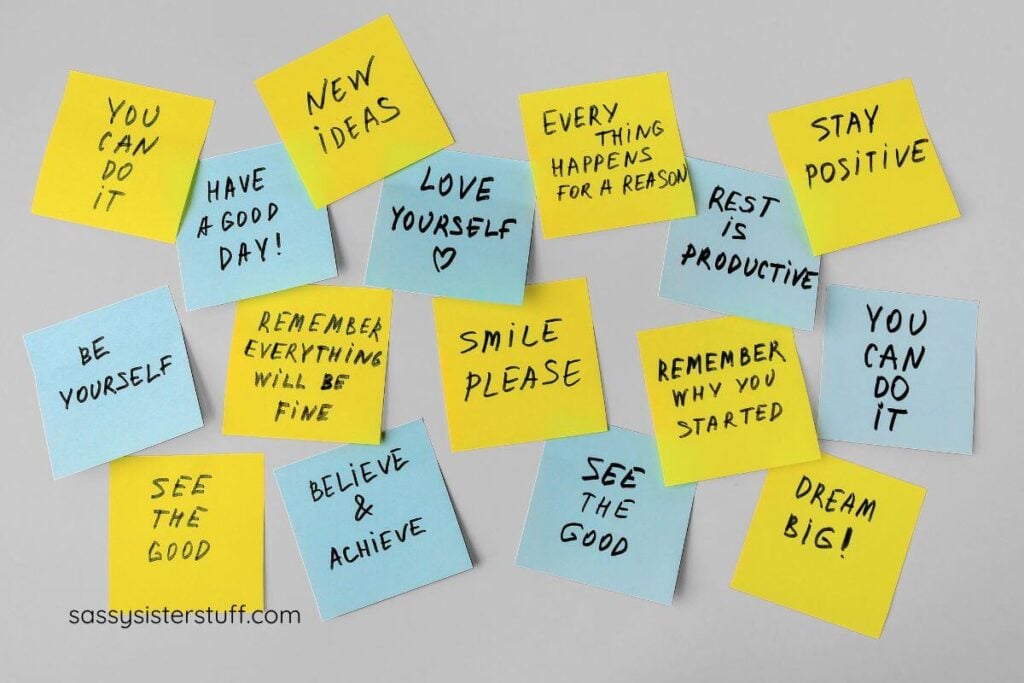 a gray wall covered with yellow and blue sticky notes that have positive affirmations on them.