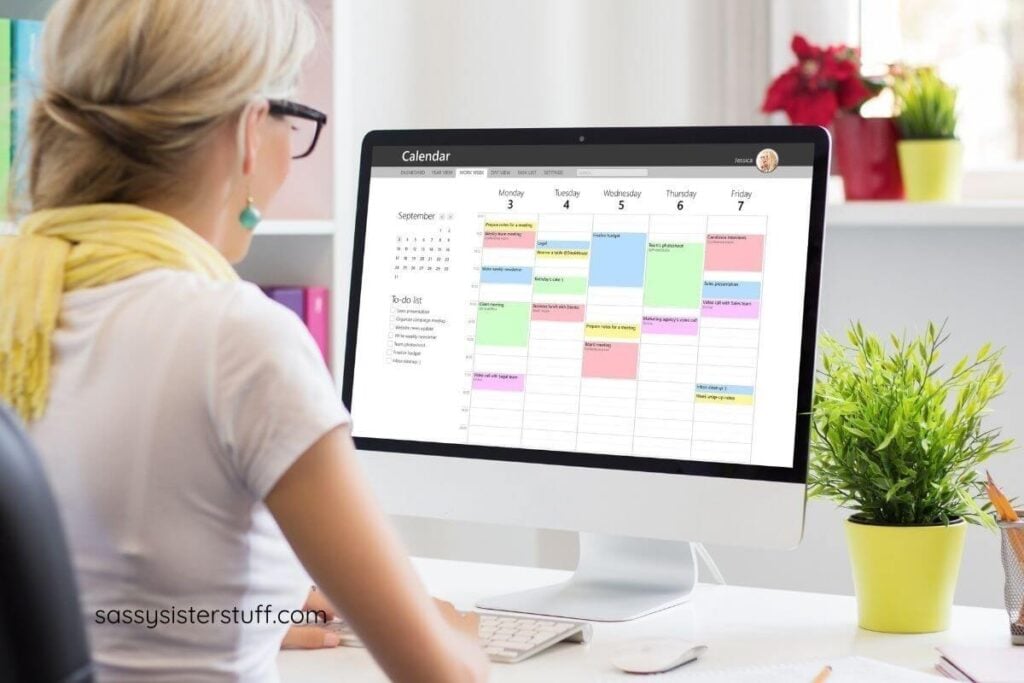 woman looks at a computer screen with a color coded calendar on the screen.