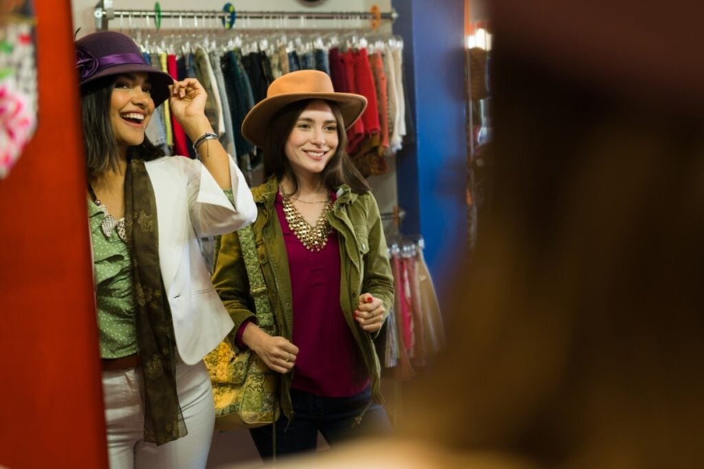 Customer trying on new clothes in a dressing room mirror at the shopping mall, enjoying her retail therapy experience