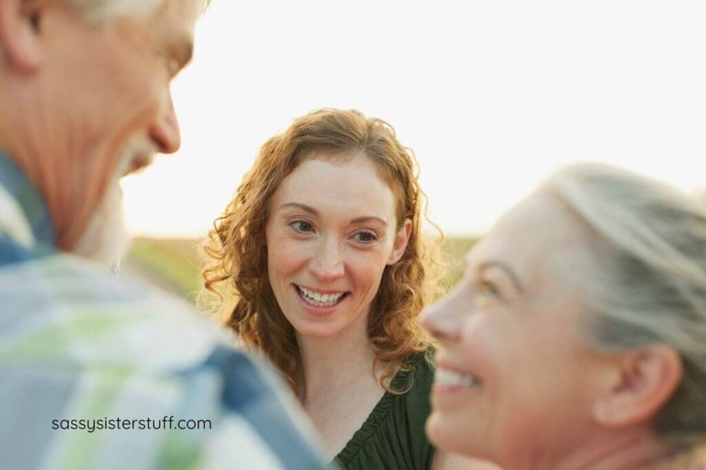 a grown adult woman smiles charmingly at her aging parents.