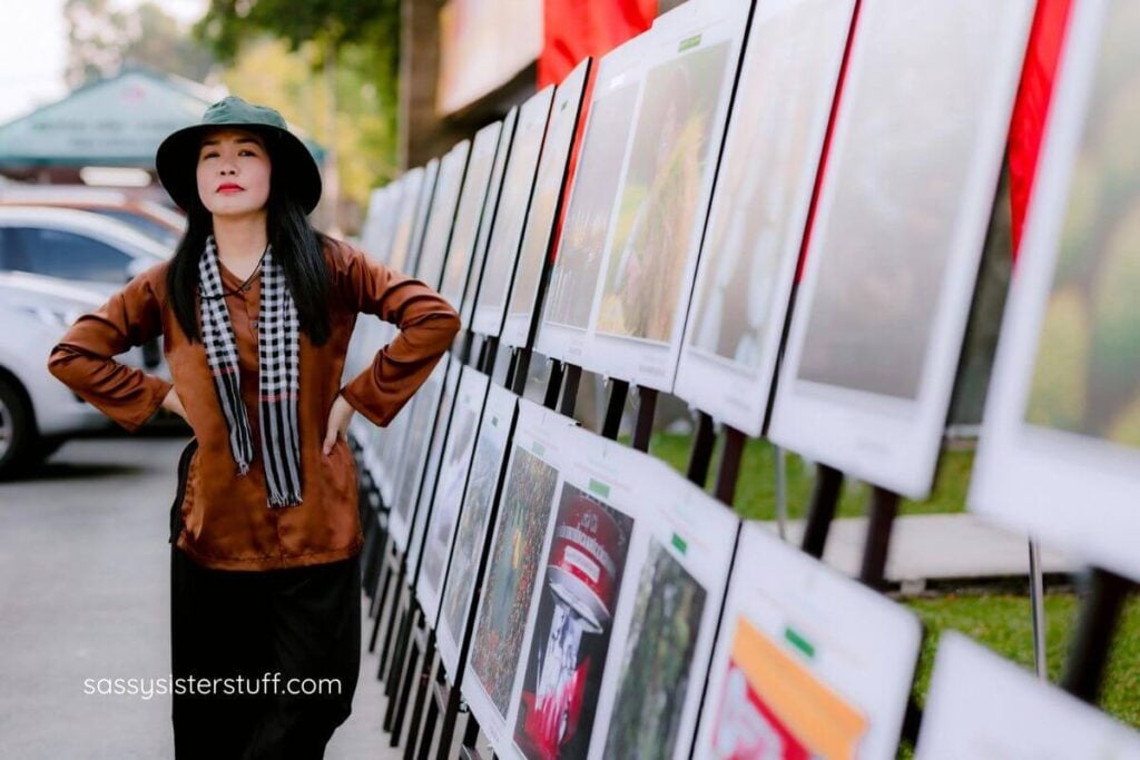 an artist standing in front of her display of artwork at a craft festival.