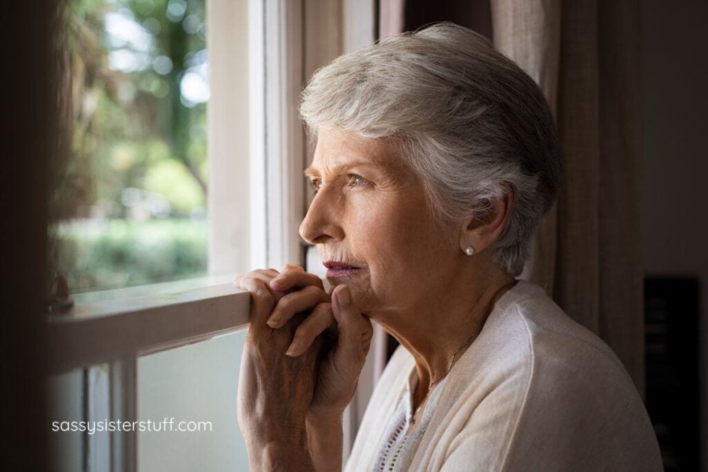 middle aged woman sadly looking out a window.