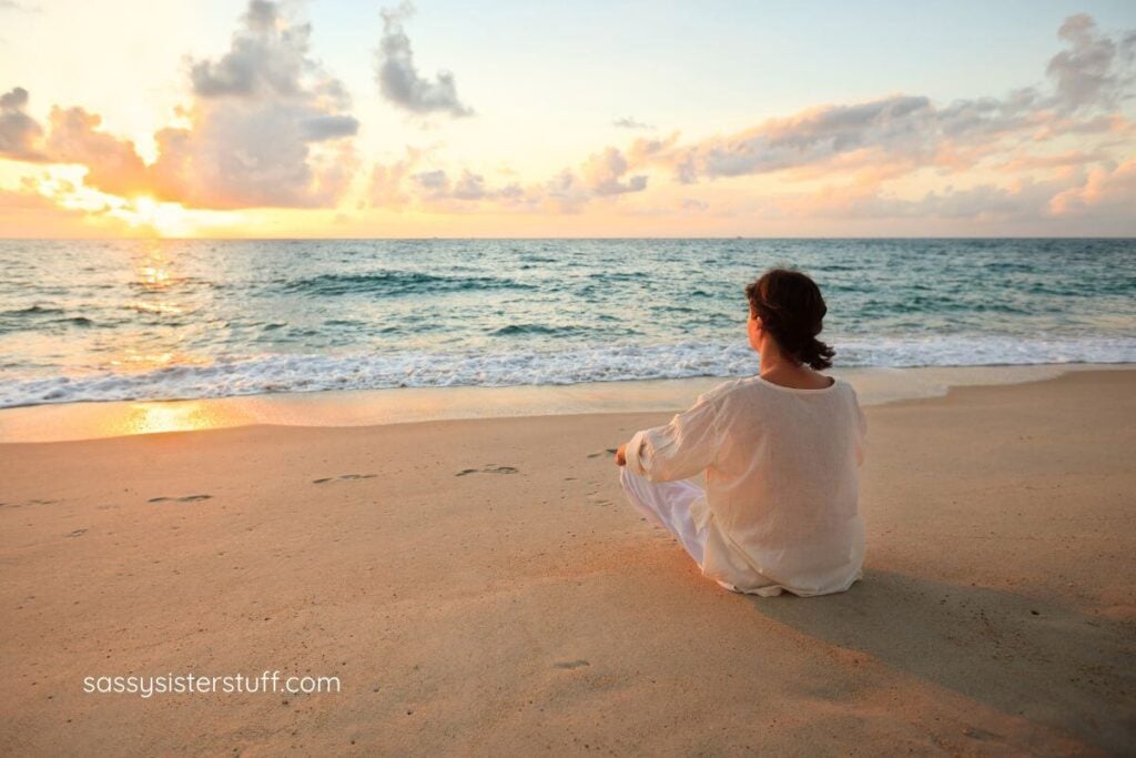 woman sitting in a yoga pose on the beach as she tries to overcome the sadness of her child going no-contact.