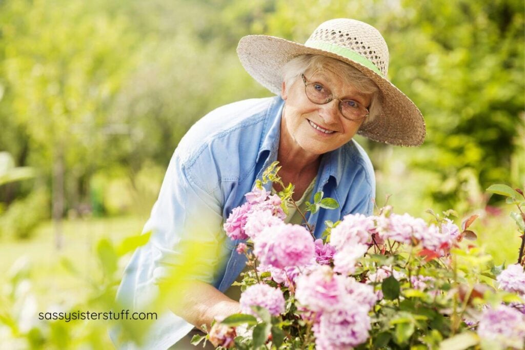 happy middle aged woman does her gardening with beautiful pink flowers.