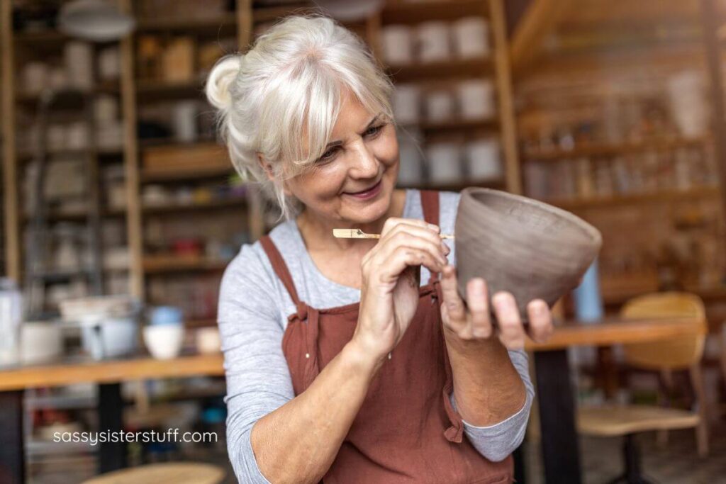happy middle aged woman with beautiful silver hair does her pottery.