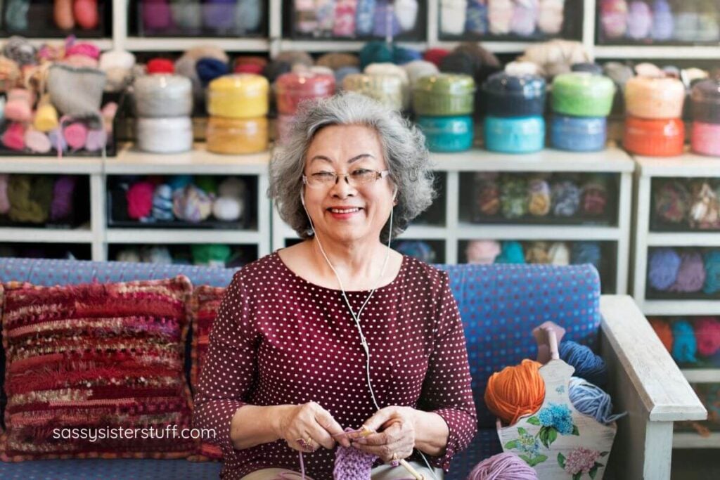happy middle aged Asian woman crochets.